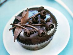 there is a chocolate cupcake with icing and cinnamons on the top, sitting on a white plate