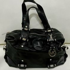 Michael Kors Black Leather Handbag With Silver Hardware, Includes Shoulder Strap, Inside Has Zipper Pocket, Four Pockets, One Additional Pocket In The Outer Front With Logo Lining And Hanging Metal Logo Medallion. Approximately 13” W X 7” H X 4” D. Leather Satchel With Logo Hardware, Silver Leather Bags With Logo Hardware, Luxury Silver Bag With Logo Hardware, Silver Bags With Logo Hardware For Formal Occasions, Formal Silver Shoulder Bag With Logo Hardware, Formal Silver Bags With Logo Hardware, Luxury Michael Kors Shoulder Bag With Logo Hardware, Michael Kors Formal Bag With Logo Hardware, Formal Michael Kors Bag With Logo Hardware