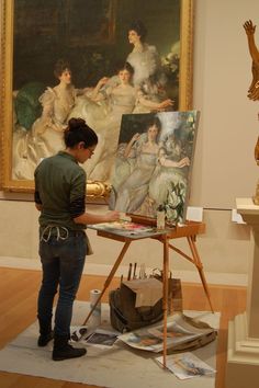 a woman is painting in an art gallery