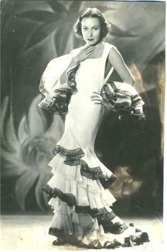 an old photo of a woman in a dress with ruffles on the skirt