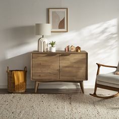 a living room with a rocking chair next to a wooden cabinet and lamp on top of it