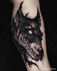 a black and white photo of a dragon tattoo on the left leg, with its eyes open