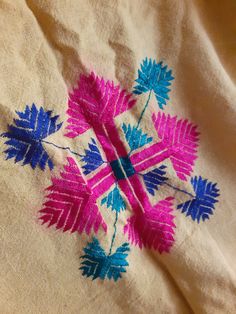 an embroidered piece of cloth with blue and pink flowers on it