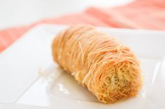 a croissant on a white plate sitting on a red and white table cloth