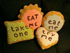 three decorated cookies that say eat me, take me, and they are on a couch