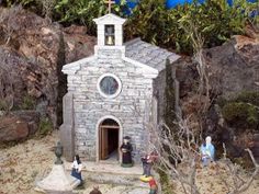 a small church made out of rocks with figurines on the ground around it