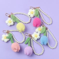 crochet keychains with flowers and pearls hanging from them on a purple background