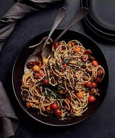 a black plate topped with spaghetti and tomatoes