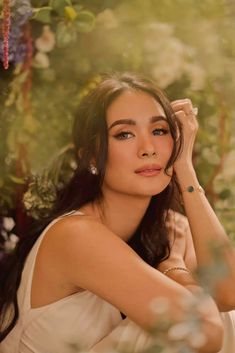 a woman sitting in front of flowers with her hand on her head