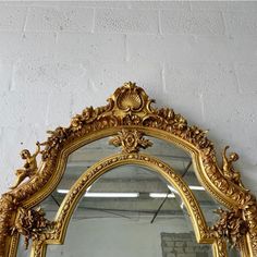 an ornate gold framed mirror against a white wall