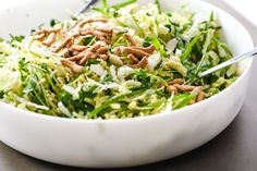 a white bowl filled with salad topped with pecans and green onions next to a fork