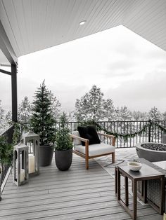 an outdoor deck with potted plants and chairs on it, overlooking the snow - covered landscape