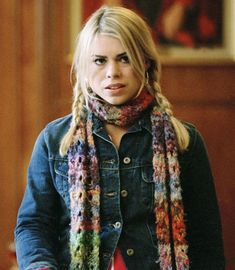 a woman with long blonde hair wearing a multicolored scarf and denim jacket is looking at the camera