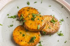 three pieces of cooked pineapple on a plate with parsley sprinkled on top