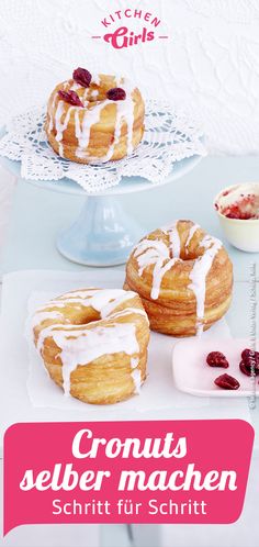 two cronuts with white icing and cherries are on a table next to other pastries