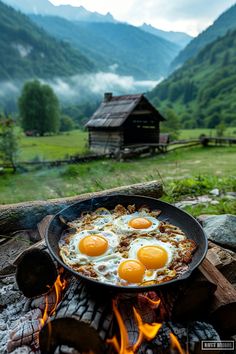 two fried eggs on top of an iron skillet in front of a campfire