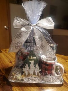 a gift basket with coffee mugs and snowflakes on the side, wrapped in clear cellophane