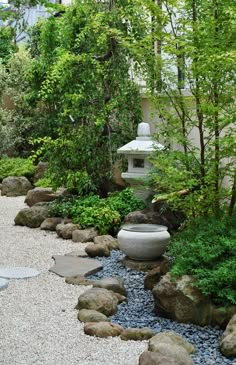 an outdoor garden with rocks and plants in the foreground, water flowing through it