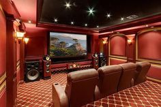 a home theater with red walls and brown leather recliners in front of the screen