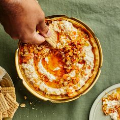 a person dipping some kind of food into a bowl with crackers on the side