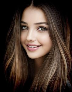 a close up of a woman with long hair and blue eyes smiling at the camera