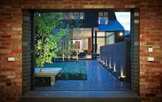 an open door to a brick house with a table and bench in the front yard