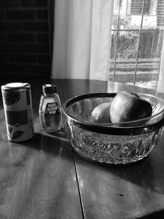 apples and honey sit on a table in front of a glass bowl with an apple