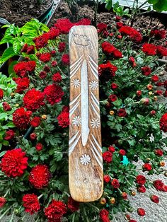 a wooden snowboard sitting in the middle of some flowers