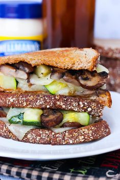 a grilled sandwich with mushrooms, zucchini and cheese on a white plate