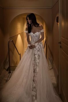 a woman in a wedding dress is standing on the stairs with her hands behind her back