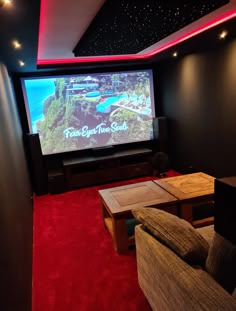 a home theater room with red carpeting and walls that have a large screen on the wall