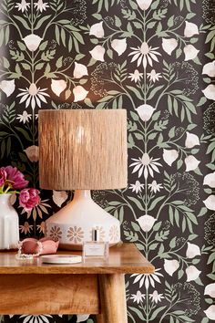 a wooden table topped with a lamp next to a vase filled with pink and white flowers