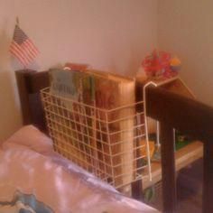 a basket is sitting on top of a bed next to a baby crib and american flag