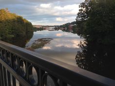 a river with trees and clouds reflected in the water on a bridge over which there is no traffic