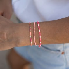 a woman's arm with two bracelets on it, one is pink and the other is white