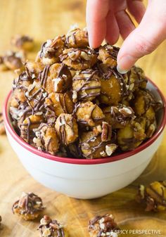 a hand is picking up some nuts from a bowl