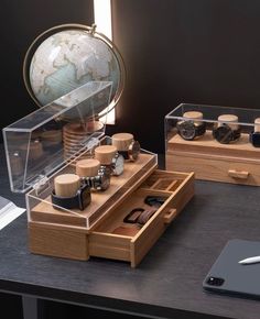 two wooden drawers with various items in them on a table next to a cell phone