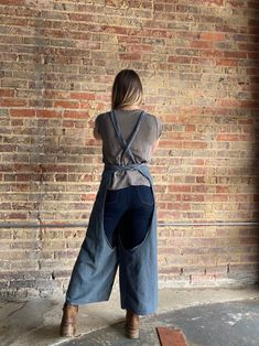 a woman standing in front of a brick wall with her back turned to the camera