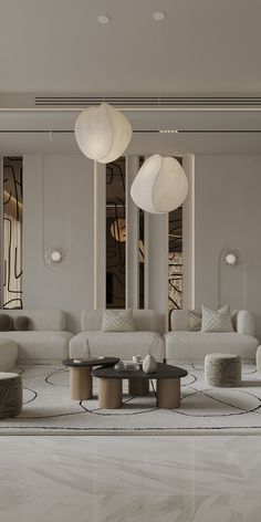 a living room filled with lots of white furniture and lamps hanging from the ceiling above