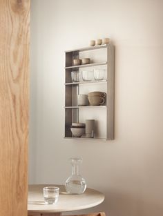 a white table with some glass vases on top of it next to a wooden shelf