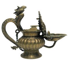 an ornate brass teapot with two birds on it's handle and chain hanging from the side