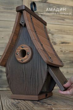 a bird house made out of wood with a hole in the roof and one hand holding it