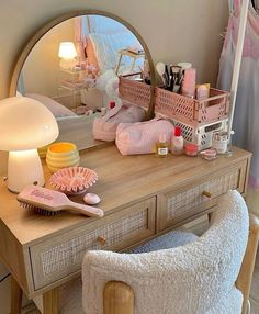 a vanity with a mirror, lamp and various items on it in front of a bed