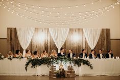 a group of people sitting at a table in front of white drapes and lights