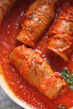 three pieces of meat covered in sauce and garnished with parsley