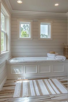 a large bathroom with white walls and wooden floors, along with two windows that look out onto the outdoors