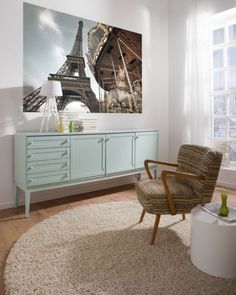 a living room with a rug, chair and painting on the wall in front of it