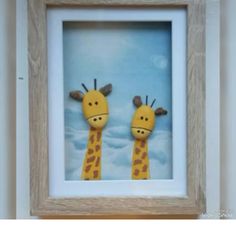 two stuffed giraffes are in a frame on the wall next to each other