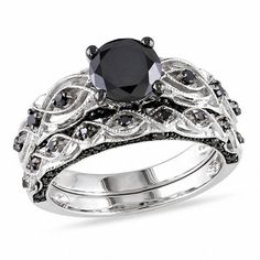 On the day you ask for her hand in marriage, express your love with this bold and elegant black diamond bridal set. Crafted in 10K white gold The engagement ring features a 1 ct. black diamond center stone. The shank features sculpted and milgrain detailing and additional black diamonds while additional black diamonds set at the top and bottom of the shank ensure sparkle from every angle. On your wedding day, the coordinating black diamond wedding band completes the ensemble. This bridal set shi Swirl Engagement Ring Set, Black Diamond Bridal Set, Swirl Engagement Rings, Black Diamond Wedding Rings, Black Diamond Wedding Bands, Gothic Engagement Ring, Infinity Engagement Ring, White Gold Bridal Set, Diamond Bridal Ring Sets