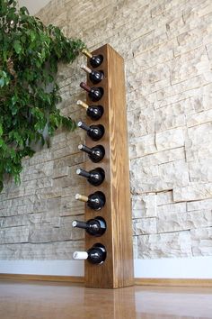 a wooden wine rack with several bottles in it next to a brick wall and potted plant